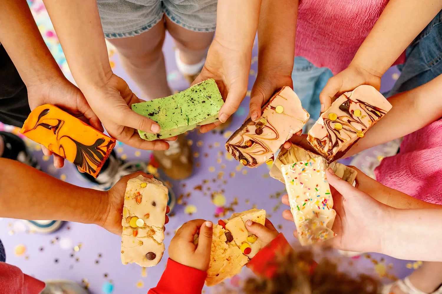 Children's hands holding colorful ice cream sandwiches on a festive background