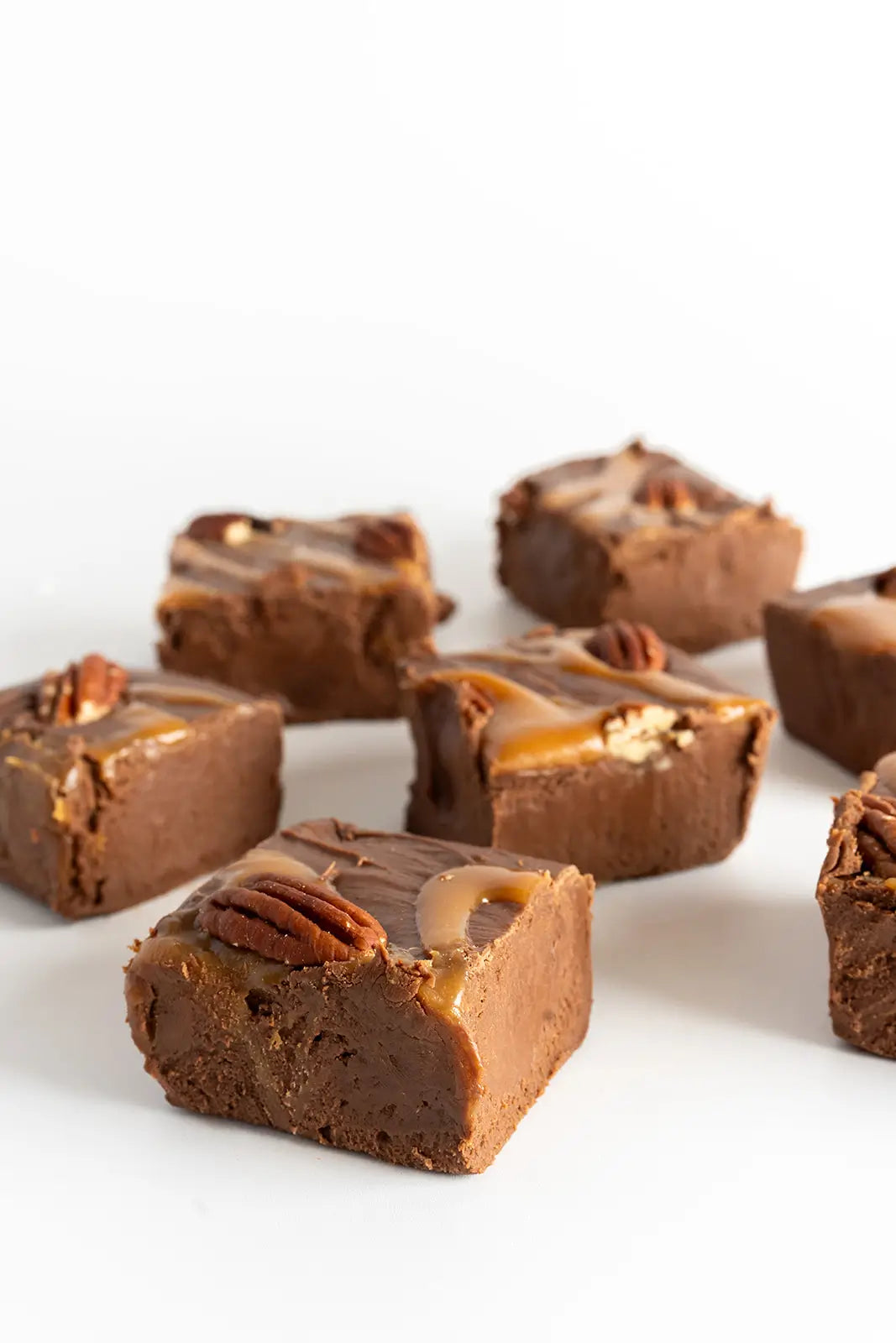 Chocolate fudge pieces with pecans on a white background