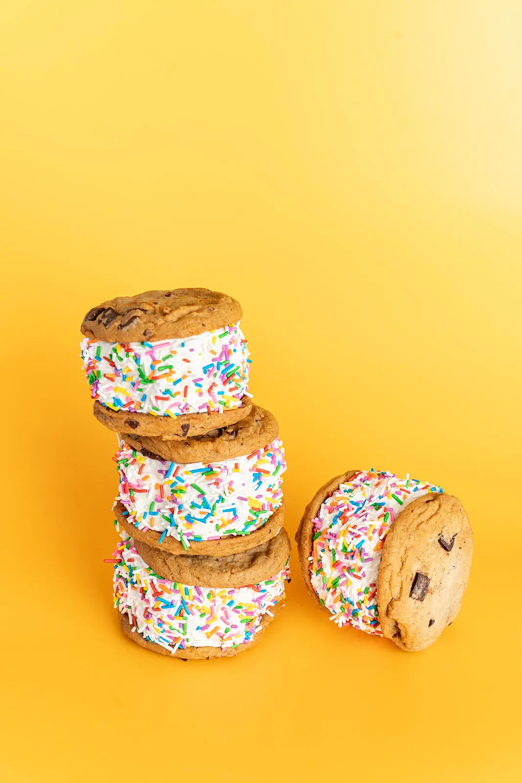 Stack of ice cream sandwiches with colorful sprinkles on a yellow background