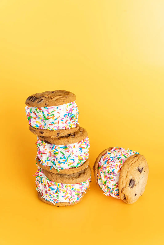 Stack of ice cream sandwiches with colorful sprinkles on a yellow background